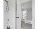 Clean, bright, white tiled bathroom with a shower and a view to a carpeted hallway and stairway at 4574 Walden St, Denver, CO 80249