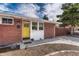 Close up view of a brick ranch with yellow front door and well maintained rock landscaping at 1906 S Vrain St, Denver, CO 80219