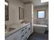 Bathroom featuring double sinks with marble countertops, a soaking tub, and white cabinets at 16639 E Berry Ln, Centennial, CO 80015