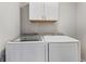 Convenient laundry room includes modern washer and dryer set with overhead cabinet storage at 6835 Surrey Trl, Littleton, CO 80125
