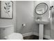 Stylish half bathroom featuring a pedestal sink, round mirror, and modern fixtures at 11861 E Yale Ct, Aurora, CO 80014