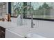 Close-up of a kitchen sink with modern faucet, white countertops, and a window view at 11861 E Yale Ct, Aurora, CO 80014