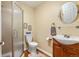 Classic bathroom featuring shower with glass door, wood vanity, and circular mirror at 1851 E 138Th Ave, Brighton, CO 80602