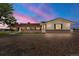Dusk view of the ranch-style home featuring a brick facade, covered porch and a gravel driveway at 1851 E 138Th Ave, Brighton, CO 80602