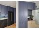 A modern kitchen featuring a black refrigerator, stove, range hood and dishwasher with navy and wood cabinets at 550 E 12Th Ave # 810, Denver, CO 80203
