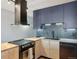 A modern kitchen featuring a black stove, range hood and dishwasher with navy and wood cabinets at 550 E 12Th Ave # 810, Denver, CO 80203