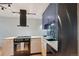 A modern kitchen featuring a black stove, range hood and dishwasher with navy and wood cabinets at 550 E 12Th Ave # 810, Denver, CO 80203