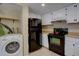 White cabinets, black appliances, tile flooring, washer in kitchen at 562 W Crestline Cir # 7D, Littleton, CO 80120