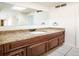 Bathroom vanity featuring granite countertop, dark wood cabinets, large mirror, and natural lighting from skylight at 1233 S Yosemite Way # 74, Denver, CO 80247