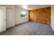 Bedroom with wood accent wall, neutral carpet, white walls, and a window overlooking a pleasant street view at 1233 S Yosemite Way # 74, Denver, CO 80247