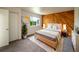 Bedroom with wood accent wall, neutral carpet, white walls, and a stylish bed with plant decoration at 1233 S Yosemite Way # 74, Denver, CO 80247