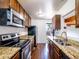 Galley kitchen with stainless steel appliances, including microwave, oven, and fridge and granite countertops at 1233 S Yosemite Way # 74, Denver, CO 80247