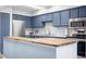 Modern kitchen with stainless steel appliances, a wood-topped breakfast bar, and blue cabinetry at 4301 S Pierce St # 6D, Littleton, CO 80123