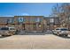 Three-unit townhouse exterior showing brick facade and parking spaces in front on a sunny day at 14462 E Mississippi Ave # B, Aurora, CO 80012