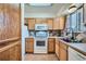 Functional kitchen with wooden cabinets, white appliances, and tile flooring with matching backsplash at 14462 E Mississippi Ave # B, Aurora, CO 80012