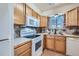 Well-lit kitchen with wooden cabinets, white appliances, and a window with decorative curtains at 14462 E Mississippi Ave # B, Aurora, CO 80012