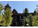Unique Tudor-style home exterior with a tower and stone accents, surrounded by lush green trees at 2140 S Ash St # 102, Denver, CO 80222