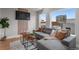 Open living room with grey sofa, wood accent wall and a large window at 2140 S Ash St # 102, Denver, CO 80222