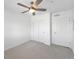 Bright bedroom with neutral carpet features a ceiling fan, closet, and two white doors at 1062 Rockhurst Dr # 302, Highlands Ranch, CO 80129