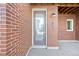Charming front entrance with a red brick facade and modern frosted glass door at 7812 W 43Rd Pl, Wheat Ridge, CO 80033