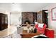 Inviting living room featuring a brick fireplace, hardwood floors, and cozy red furnishings at 6495 E Happy Canyon Rd # 114, Denver, CO 80237