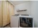 Bright laundry room with washer, dryer, shelf, and curtained area for storage at 19120 E 54Th Pl, Denver, CO 80249