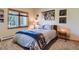 Cozy bedroom with a large window, neutral carpet, and bed with blue accents at 2012 Tournament Ct, Evergreen, CO 80439