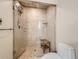 Walk-in shower with glass door and ceramic tile surround, bench, and toilet at 2012 Tournament Ct, Evergreen, CO 80439