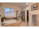 Bright bathroom featuring a soaking tub, glass shower, and closet space at 15333 Heritage Cir, Thornton, CO 80602