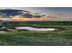 Scenic community view featuring a pond, lush green space, and vibrant sunset colors at 15333 Heritage Cir, Thornton, CO 80602