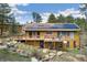 Beautiful home featuring a large deck, solar panels, and a natural rock landscape at 11398 Ranch Elsie Rd, Golden, CO 80403