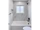 Modern bathroom with marble tile, updated black fixtures, and a shower-tub combination at 1455 S Tennyson St, Denver, CO 80219