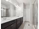 Bright bathroom featuring double sinks, a large mirror, dark cabinets, tile floors and glass-enclosed shower at 9269 Garnett St # C, Arvada, CO 80007