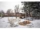 Inviting backyard with a cozy fire pit and seating area, surrounded by mature trees and a blanket of snow at 1205 Lee St, Lakewood, CO 80215