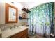 Cozy bathroom with wood-framed mirror, wooden shelves, forest-themed shower curtain, and tiled floor at 1205 Lee St, Lakewood, CO 80215