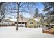 Charming single-story home with a brick chimney, adjacent carport, and a spacious snow-covered yard at 1205 Lee St, Lakewood, CO 80215