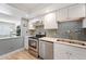Updated kitchen with stainless steel appliances, white cabinetry, light countertops, and tile backsplash at 13952 E Marina Dr # 310, Aurora, CO 80014