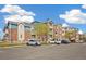 A wide angle view of a brick apartment complex showcasing ample parking and manicured landscaping at 2662 S Cathay Way # 302, Aurora, CO 80013