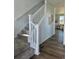Elegant staircase with carpeted steps, white railing, and hardwood floors in a bright, open space at 6077 Idlewild Pl, Brighton, CO 80601