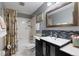 Updated bathroom featuring a vanity with a black cabinet, a modern mirror, and a shower-tub combination at 3752 S Rosemary Way, Denver, CO 80237