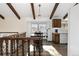 Charming dining area with wood beams, decorative lighting, and wood floors adjacent to a white kitchen with modern appliances at 3752 S Rosemary Way, Denver, CO 80237