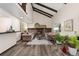 Open living room featuring a stone fireplace, wood floors, high vaulted ceilings with exposed beams, and neutral-toned furniture at 3752 S Rosemary Way, Denver, CO 80237