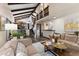 Spacious living room featuring wood floors, high ceilings with beams, bar area, and access to the staircase at 3752 S Rosemary Way, Denver, CO 80237