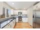 Modern kitchen with white cabinets, stainless steel appliances, granite countertops, and light-colored hardwood floors at 777 Whispering Oak Dr, Castle Rock, CO 80104