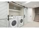 Convenient laundry room with modern washer and dryer, shelving, and a sliding barn door at 777 Whispering Oak Dr, Castle Rock, CO 80104