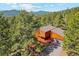 Aerial view of a rustic home nestled among lush evergreen trees in the mountains at 1278 Aspen Dr, Evergreen, CO 80439