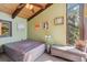 Cozy bedroom with art, a view window, exposed ceiling beams, and an upholstered bench at 1278 Aspen Dr, Evergreen, CO 80439