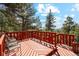 Inviting wood deck with red railing offers scenic views of surrounding trees and mountains at 1278 Aspen Dr, Evergreen, CO 80439