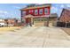 Charming two-story home with red siding, stone accents, a three-car garage, and a well-maintained front yard at 4736 S Buchanan St, Aurora, CO 80016