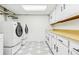 Functional laundry room with washer, dryer, utility sink and ample storage space with cabinets and shelves at 14582 E Harvard Ave, Aurora, CO 80014